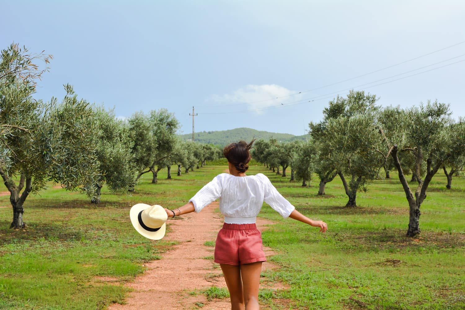 girl is running through olive tree field in ibiza