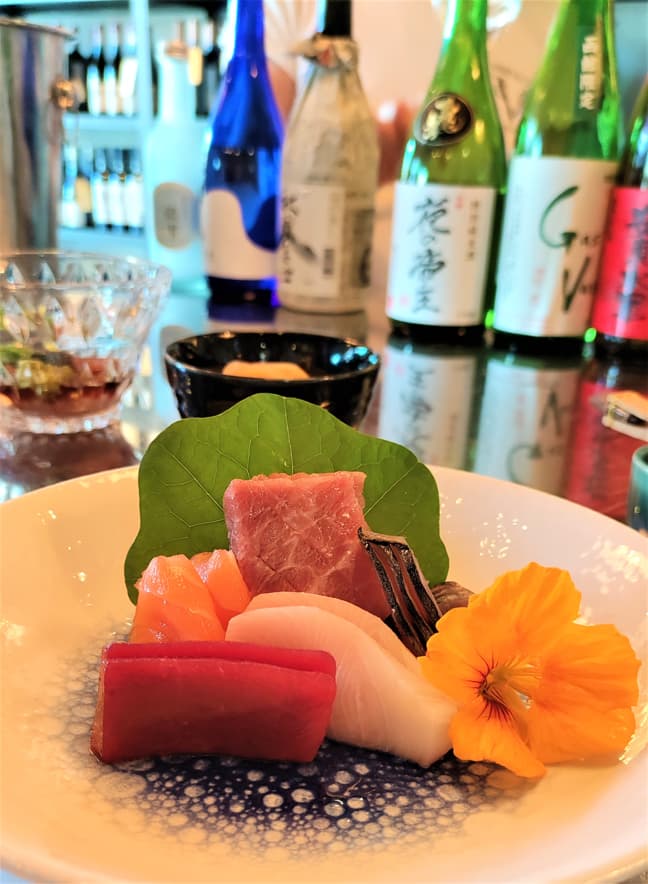 Sashimi plate, bottle of sake in the background